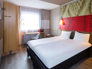 
a hotel room with a large bed and a large window at ibis De Haan in De Haan
