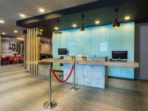 a lobby with a reception counter with a red hose at ibis De Haan in De Haan