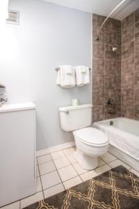 La salle de bains est pourvue de toilettes, d'une baignoire et d'un lavabo. dans l'établissement APM Inn & Suites, à Martinsburg