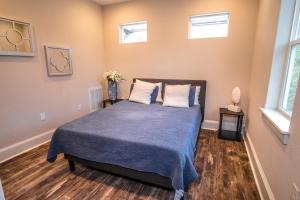 um quarto com uma cama com um cobertor azul e duas janelas em Beautiful Guest House on New Built Home Near Downtown em San Antonio