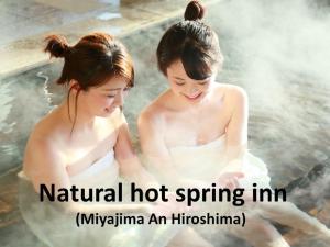Due donne sedute in acqua in una sorgente termale di Ryokan with natural hot springs and okonomiyaki Miyajima-an Hiroshima a Miyajima