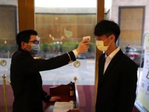 a man taking a picture of another man wearing a mask at Royal Mediterranean Hotel in Guangzhou