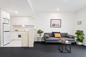 a living room with a couch and a kitchen at Quest Prahran in Melbourne