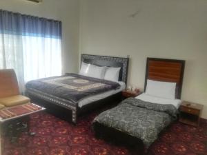 a hotel room with two beds and a chair at KHYBER INN in Islamabad