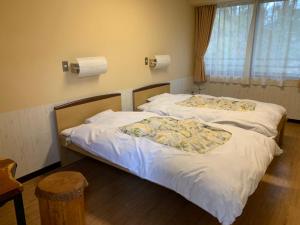 two twin beds in a room with a window at Showa Forest Village in Chiba