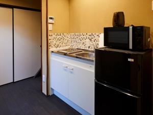 a kitchen with a sink and a microwave on top of a refrigerator at Rinn Fushimiinari in Kyoto