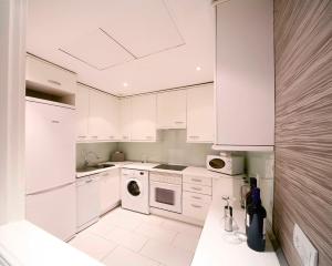 a white kitchen with white cabinets and a dishwasher at Boutike Cibeles in Madrid