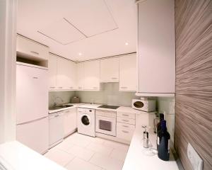 cocina blanca con armarios blancos y lavavajillas en Boutike Cibeles, en Madrid