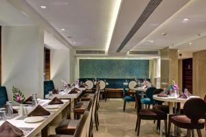 ein Restaurant mit weißen Tischen und Stühlen und einer grünen Wand in der Unterkunft The Sahil Hotel in Mumbai