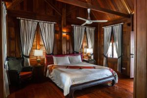 Un dormitorio con una cama y un ventilador de techo. en Burasari Heritage Luang Prabang, en Luang Prabang