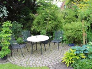 un patio con mesa y sillas en un jardín en Gaestehaus An der Fehnroute I, 11037, en Leer