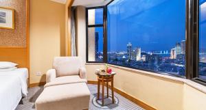 um quarto com uma cama, uma cadeira e uma janela em Millennium Harbourview Hotel Xiamen-Near Metro Station & Zhongshan Road em Xiamen