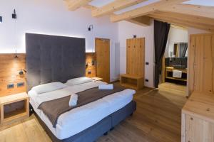 a bedroom with a large bed with a large headboard at Arnica Mountain Hotel in Soraga
