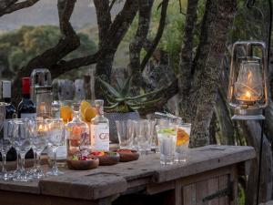 una mesa con copas y botellas de vino. en HillsNek Safari Camp – Amakhala Game Reserve en Amakhala Game Reserve