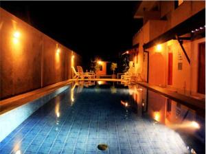 a swimming pool at night with chairs and a building at Villa 61 in Beruwala