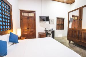 a bedroom with a large white bed and a television at Thambu Illam in Jaffna