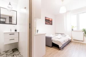 biała sypialnia z łóżkiem i lustrem w obiekcie Apartamenty Novomiejska 17 w mieście Lublin