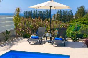 a patio with two chairs and a table with an umbrella at Sophia's Seaview Luxury Villas in Paphos
