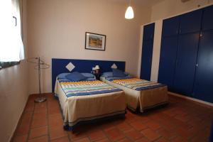 two beds in a room with blue cabinets at Casa Rural Apartamento "Isla del Zújar" in Castuera