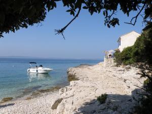 a boat in the water next to a rocky shore at Lošinj house robinson Vinodarska, Island Lošinj in Nerezine