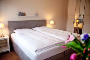 um quarto com uma cama grande e lençóis brancos em Ferienwohung Tilla em Scharbeutz