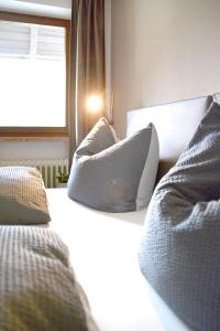 a bedroom with two beds with pillows and a window at Pension Almhof Baumgarten in Bad Reichenhall