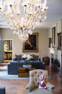 a living room with a blue couch and a chandelier at Château Ormes de Pez in Saint-Estèphe