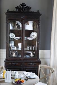 a wooden hutch with plates and dishes on a table at Château Ormes de Pez in Saint-Estèphe