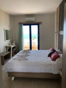 a bedroom with a large white bed with a window at Taverna Akrogiali in Loutro