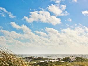 uma praia com pedras e um céu azul e nuvens em 5 person holiday home in Ringk bing em Søndervig