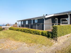 a house with a fence next to a yard at 6 person holiday home in Alling bro in Rygård Strand