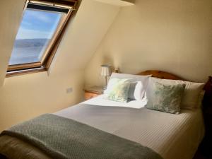 1 dormitorio con 1 cama grande y ventana en White Cottage B&B, en North Kessock