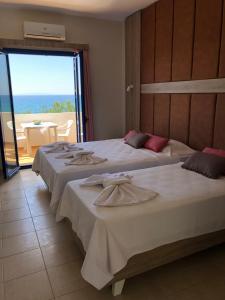 two beds in a room with a view of the ocean at Taverna Akrogiali in Loutro