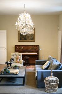 a living room with a couch and a chandelier at Château Ormes de Pez in Saint-Estèphe