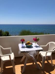 a table and chairs with a bowl of fruit on a balcony at Taverna Akrogiali in Loutro