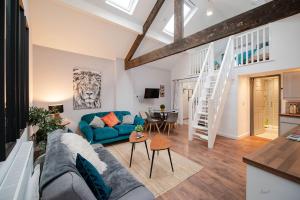 a living room with a blue couch and a staircase at Apartment 2 Broadhurst Court sleeps 6, minutes from town centre & trains in Stockport