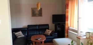 a living room with a black leather couch and a table at Ildi Apartman in Gyenesdiás