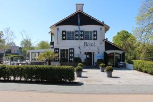 a white house with a large clock on the front of it at Strandhotel Dennenbos in Oostkapelle