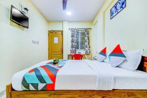 1 dormitorio con 1 cama blanca grande con almohadas coloridas en FabExpress Ragu Residency, en Coimbatore