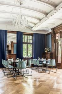 una sala da pranzo con tavoli, sedie e lampadario a braccio di Hotel Schloss Teutschenthal a Teutschenthal