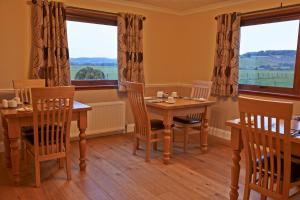 a dining room with two tables and two windows at Hillview Park in Beauly