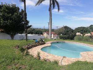 a swimming pool in a yard with palm trees at RonVu @ Bertram in East London