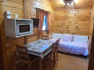 un comedor con una mesa y una cama en una cabaña en Bungalows Conca De Ter, en Vilallonga de Ter