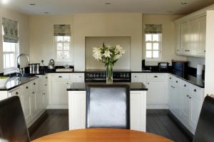 a kitchen with white cabinets and a vase of flowers on the counter at Ann's Hill in Cockermouth