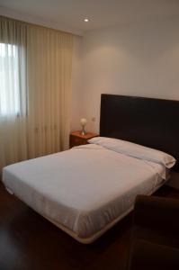 1 dormitorio con 1 cama blanca y ventana en Apartamentos de Turismo Rural Vinacua, en Sos del Rey Católico