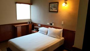 Schlafzimmer mit einem Bett mit weißer Bettwäsche und einem Fenster in der Unterkunft New May Flower Hotel in Taipeh