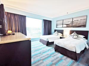 a hotel room with two beds and a large window at Thistle Johor Bahru in Johor Bahru