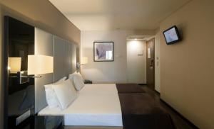 a hotel room with a bed and a tv on the wall at TURIM Luxe Hotel in Lisbon