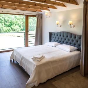 sypialnia z dużym łóżkiem i dużym oknem w obiekcie Sodyba Pelėdų medus w mieście Vainekoniai