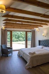 a bedroom with a large bed and a chair at Sodyba Pelėdų medus in Vainekoniai